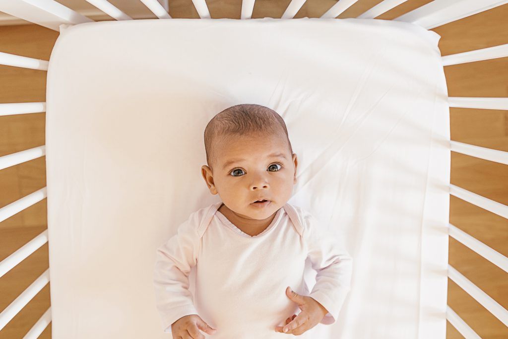 Baby lying in crib at home on their back