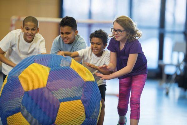 kids rolling giant ball in gym