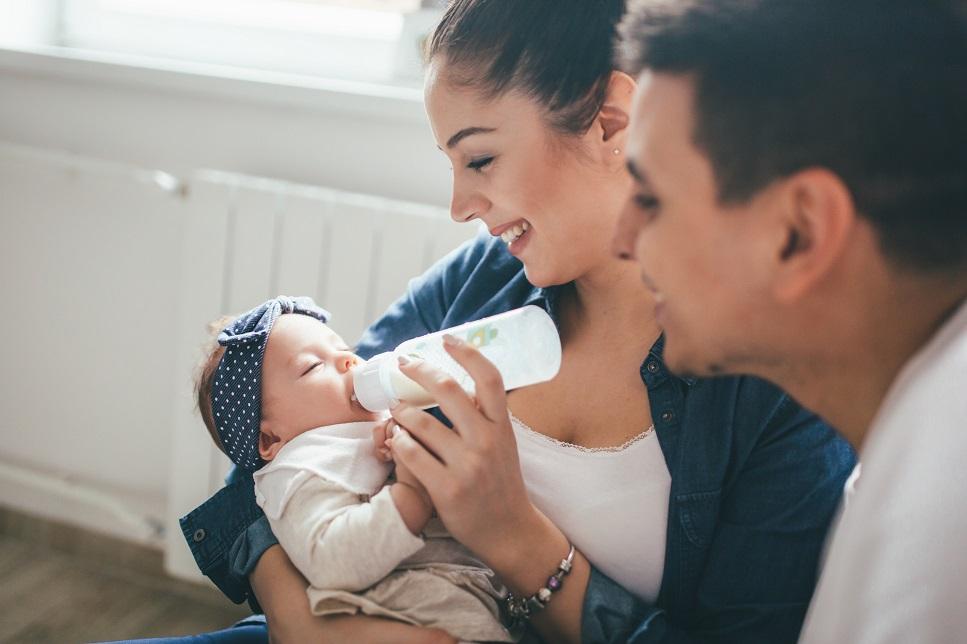 Mom and dad feeding sleeping baby