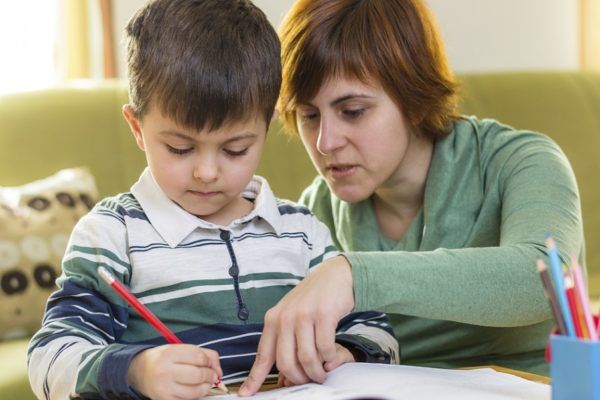 Boy doing homework with mom's help