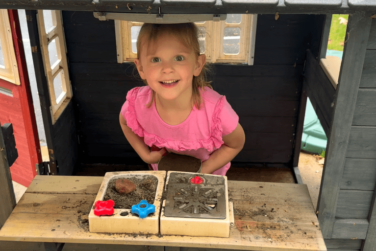 Young girl pretending her play kitchen is a fast food drive-