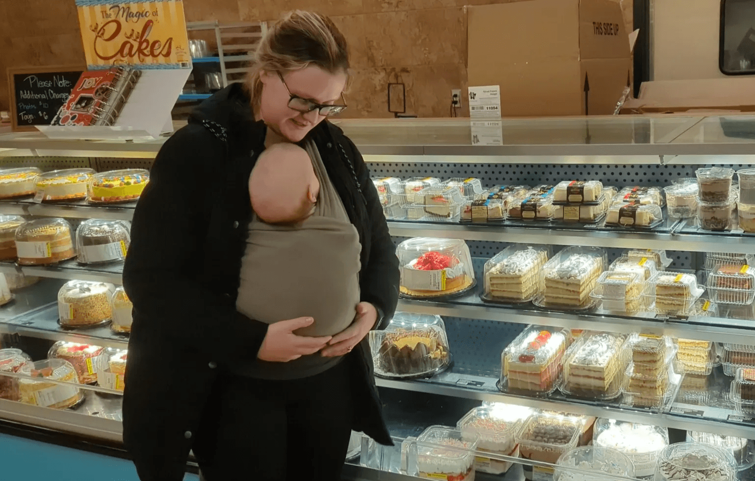 Mom holding Baby boy in wrap carrier to babywear in the grocery store.