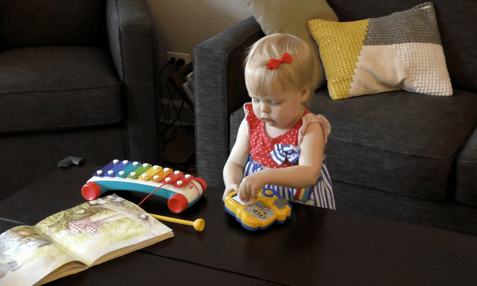 Toddler girl engaged in independent play with open-ended toys and a book