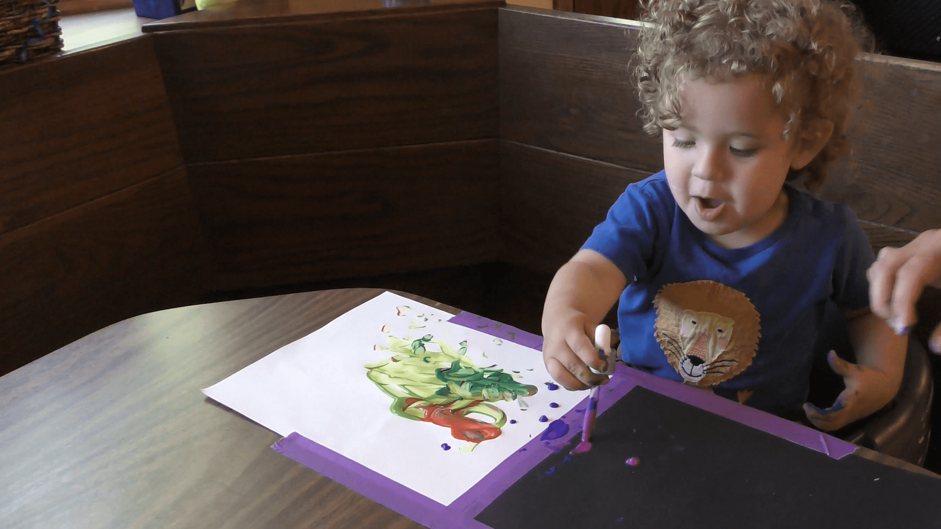 Curly-haired toddler boy makes art with an eye dropper and paint.