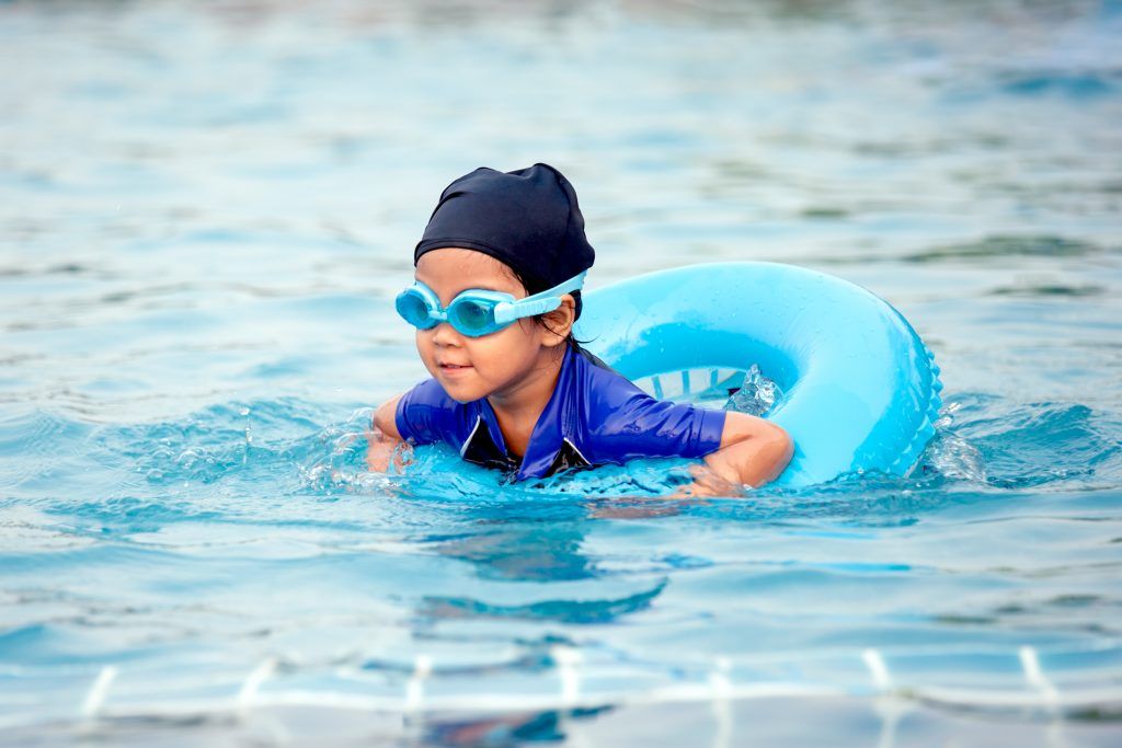 cute child swimming in pool with swim ring