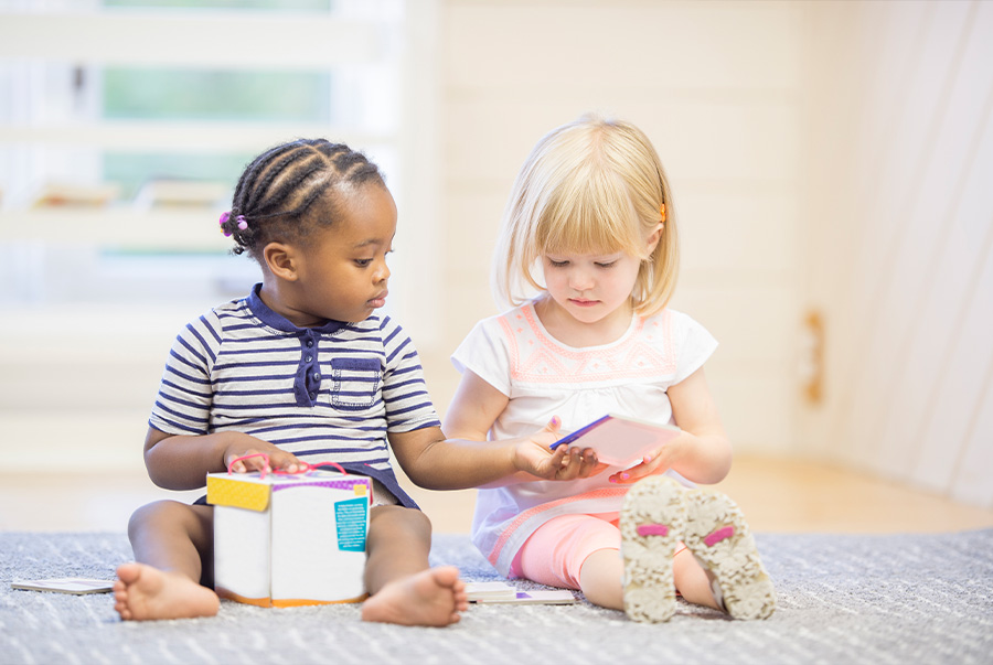 two_girls_sharing_book_during_play