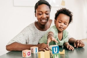 mom and toddler reaching for blocks at table
