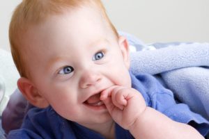 Teething baby can feel discomfort as their teeth poke out of their gums