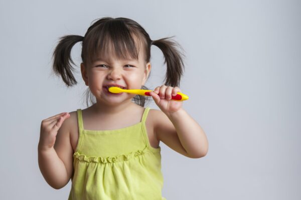 girl with pigtails brushing teeth
