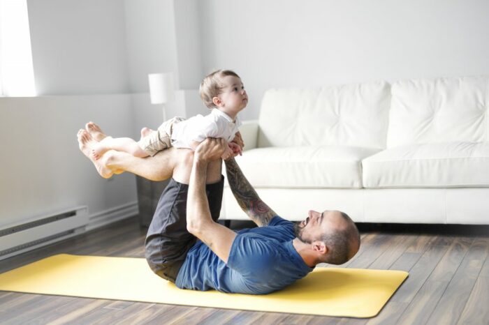 Sports man is engaged in fitness and yoga with a baby at home