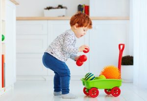 Cute-redhead-toddler-baby-collecting-different-balls-into-toy-pushcart