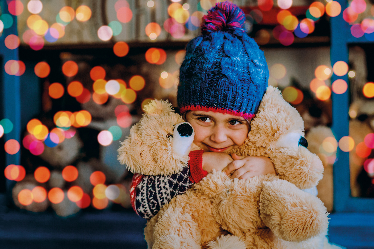 Girl with a teddy bear near lights