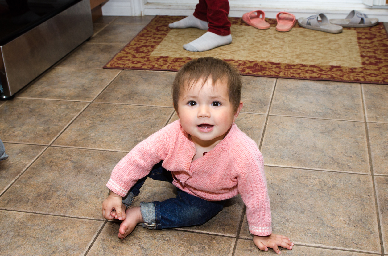baby girl sitting on kitchen floor
