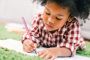kid-girl-drawing-or-painting-with-colored-pencil.-Kindergarten